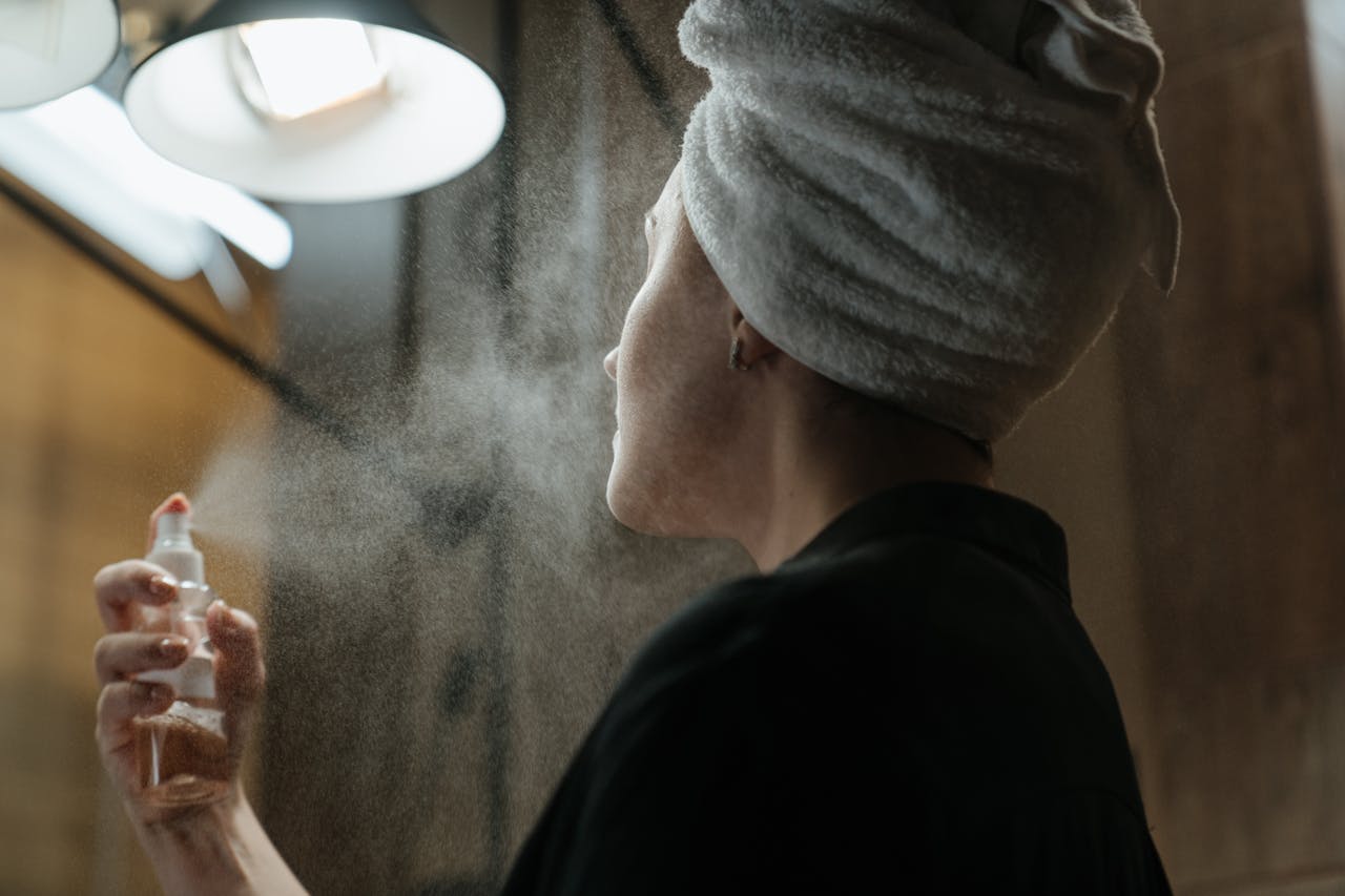Une femme utilise un spray sur son visage.